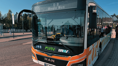 Foto: Zu sehen ist ein Bus mit der Aufschrift DB Regio, der an einer Bushaltestelle steht.