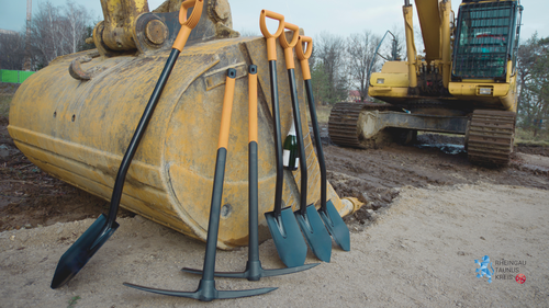 Foto: Zu sehen sind schwere Geräte auf einer Baustelle, dazu noch mehrere Spaten und anderes Werkzeug.
