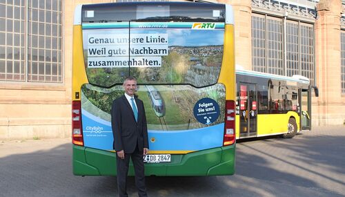 Landrat Frank Kilian vor einem Linienbus, der die gute Nachbarschaft betont. Foto: RTV