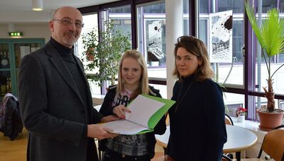 RTV-Geschäftsführer Roland Buitkamp nimmt die Unterschriftenlisten aus den Händen von Pia Hörmann von der Schülervertretung der Gesamtschule Wallrabenstein und von der Vorsitzenden der Hünstetter Liste, Anja Paulmann, entgegen.