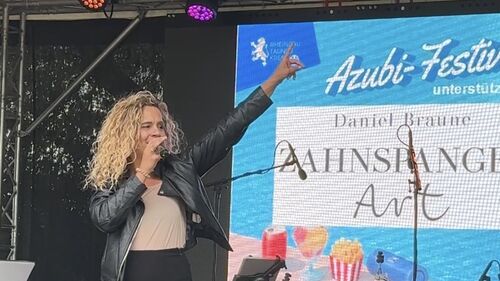 Sängerin auf der Bühne im Freibad Eltville vor dem Plakat des Azubi-Festivals.