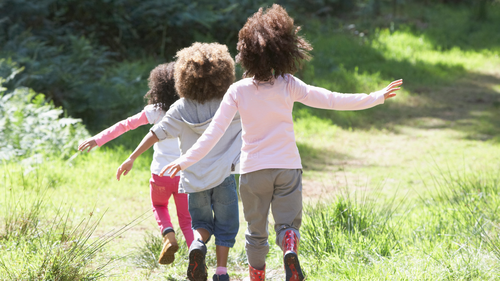Foto: Zu sehen sind Kinder, die über eine Wiese rennen.
