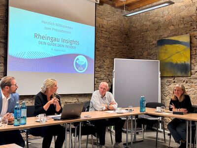 Pressetermin mit Dominik Russler, Sabine Nebel und zwei weiteren Personen vor dem BIldschirm mit der Aufschrift "Willkommen zum Pressetermin - Rheingau Insights".