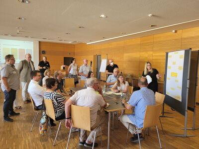 Jana Schaefer von der Hessenagentur erläutert den Teilnehmenden anhand eines Plakats Maßnahmen im Bereich „Wohnen und Versorgung".