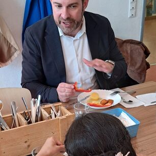 Landrat Sandro Zehner mit Schülerin am Esstisch in der Mensa.