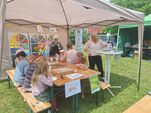 Foto: Zu sehen ist ein Pavillon mit Bänken und Tischen, an denen Kinder und Betreuer sitzen.