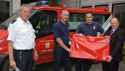 Landrat Albers überreicht Stadtbrandinspektor Torsten Lukas (2. von rechts) und Wehrführer Paul Laquai den mobilen Rauchverschluss, der sich in der Tasche befindet. Links Reiner Oswald vom Fachdienst Brand-, Katastrophenschutz und Rettungsdienst der Kreisverwaltung.