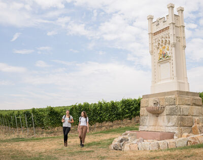 Zwei Wanderinnen laufen am Viktoria-Denkmal vorbei.