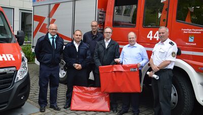 Landrat Albers überreicht Stadtbrandinspektor Sven Lillig (3. von rechts) und Michael Fischer aus Bad Schwalbach sowie Sascha Schneider und Ralf Struth jeweils einen mobilen Rauchverschluss, der sich in den roten Taschen befindet. Links Reiner Oswald vom Fachdienst Brand-, Katastrophenschutz und Rettungsdienst der Kreisverwaltung.